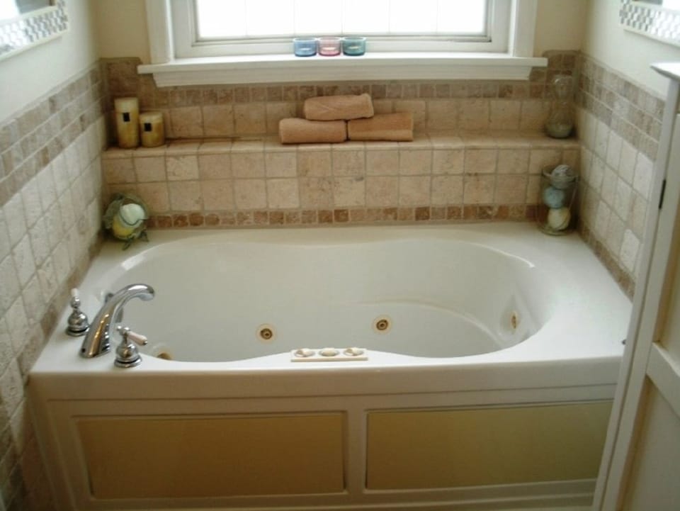 Before photo of a bathroom tub area with older wall color, tile surround, and window light