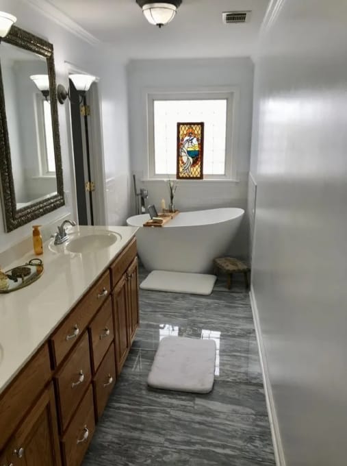 After photo of a bathroom wall finish with vanity, mirror, tub, and gray painted wall