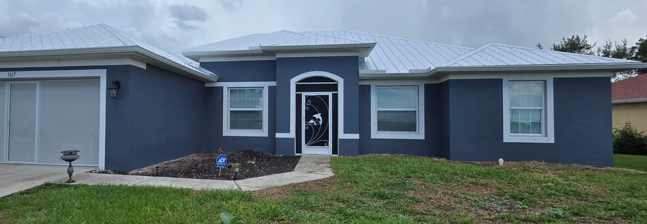 After photo of gray stucco exterior painting on a Southwest Florida home with white trim and front entry