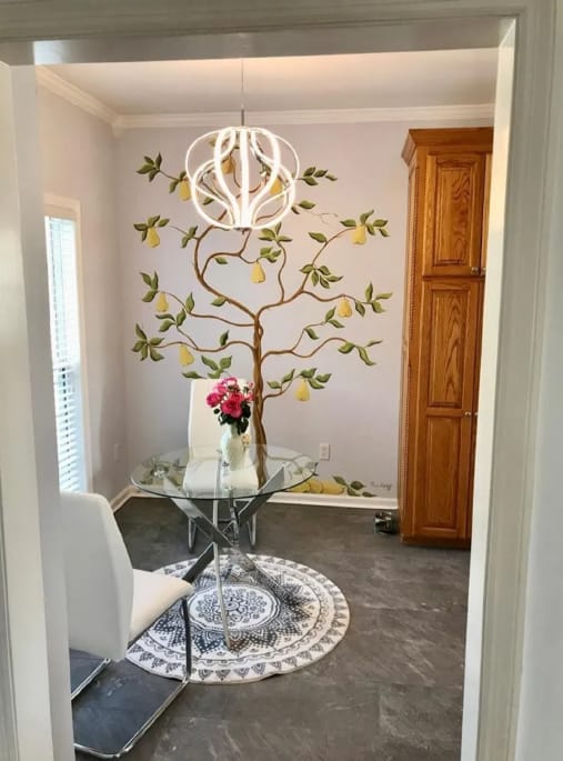 After photo of an interior dining nook with updated walls, pendant light, and floral wall detail
