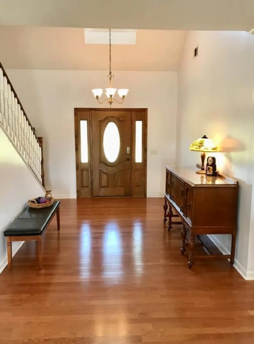 After photo of a bright interior entry wall finish with staircase and wood front door