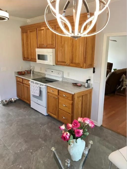 After photo of a kitchen and dining area with updated interior walls, cabinetry, and pendant lighting