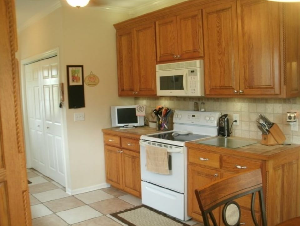 Before photo of a kitchen with older wall color around cabinets, appliances, backsplash, and trim