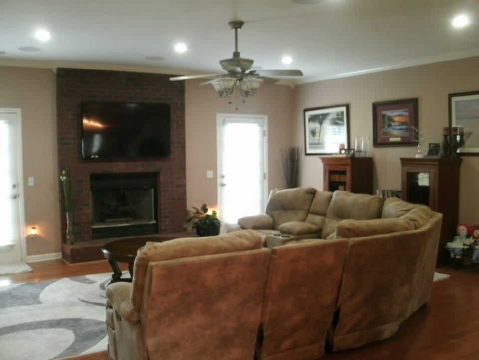 Before photo of a living room with older wall color, fireplace, seating area, and recessed ceiling lights